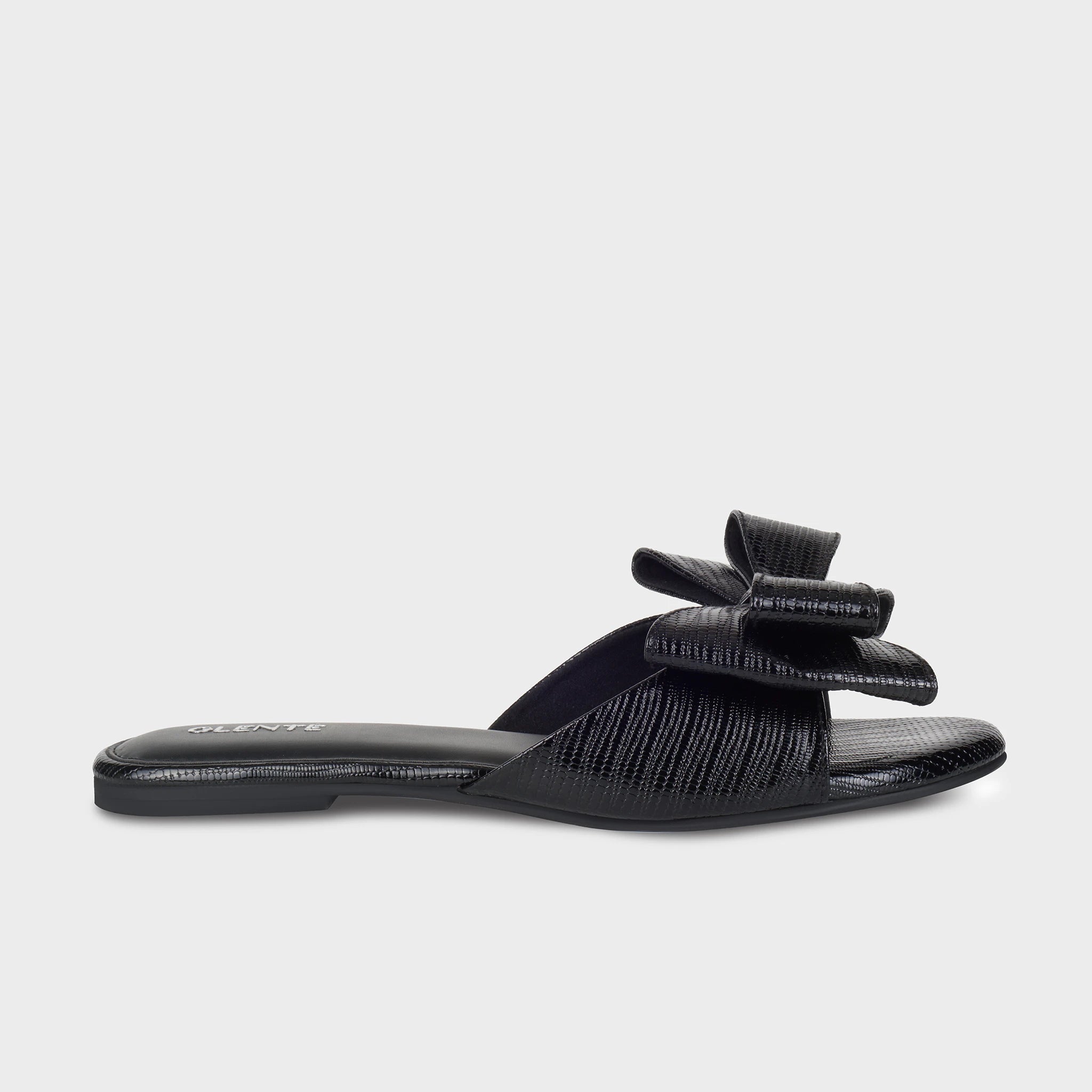 Black lizard-embossed flat slides with a sculptural double bow accent on a wide strap and silver Glentè branding on the insole - Glentè Alveria