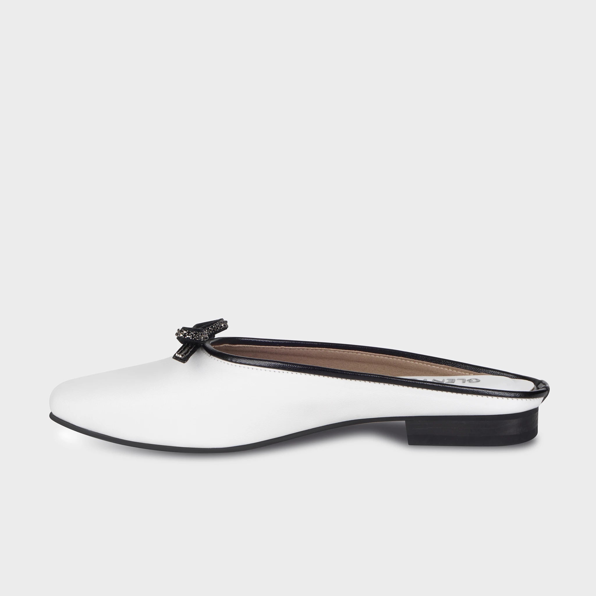 Inner side view of Auralin white flat mules showing the smooth rounded silhouette, contrast black piping along the opening, and stacked black block heel - Glentè