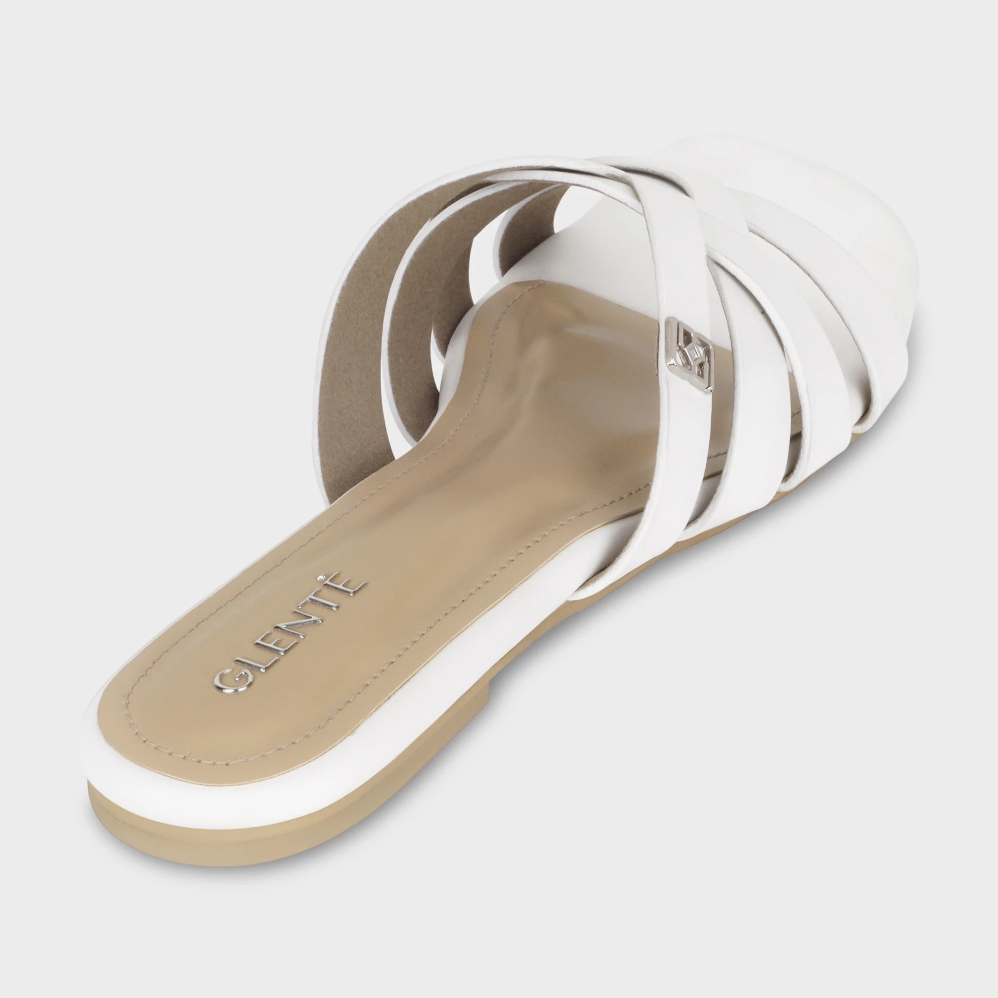Rear angled view of Averis white flat slides showing the cushioned insole with embossed silver Glentè branding, woven strap architecture, and nude outsole edge