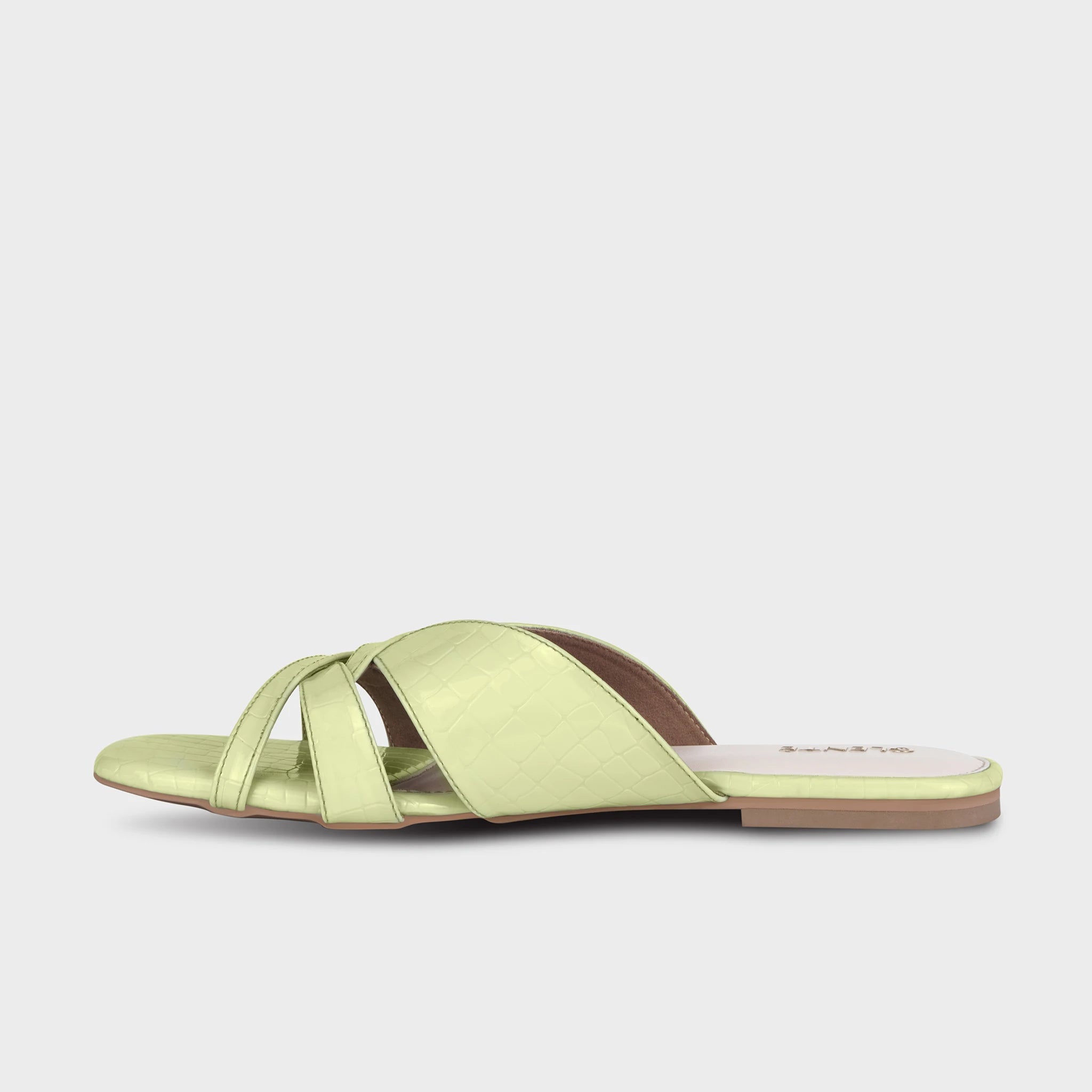 Inner side view of lime green Seraya flat slides showing the layered crossover strap profile, croc-embossed texture, and slim tan outsole — Glentè