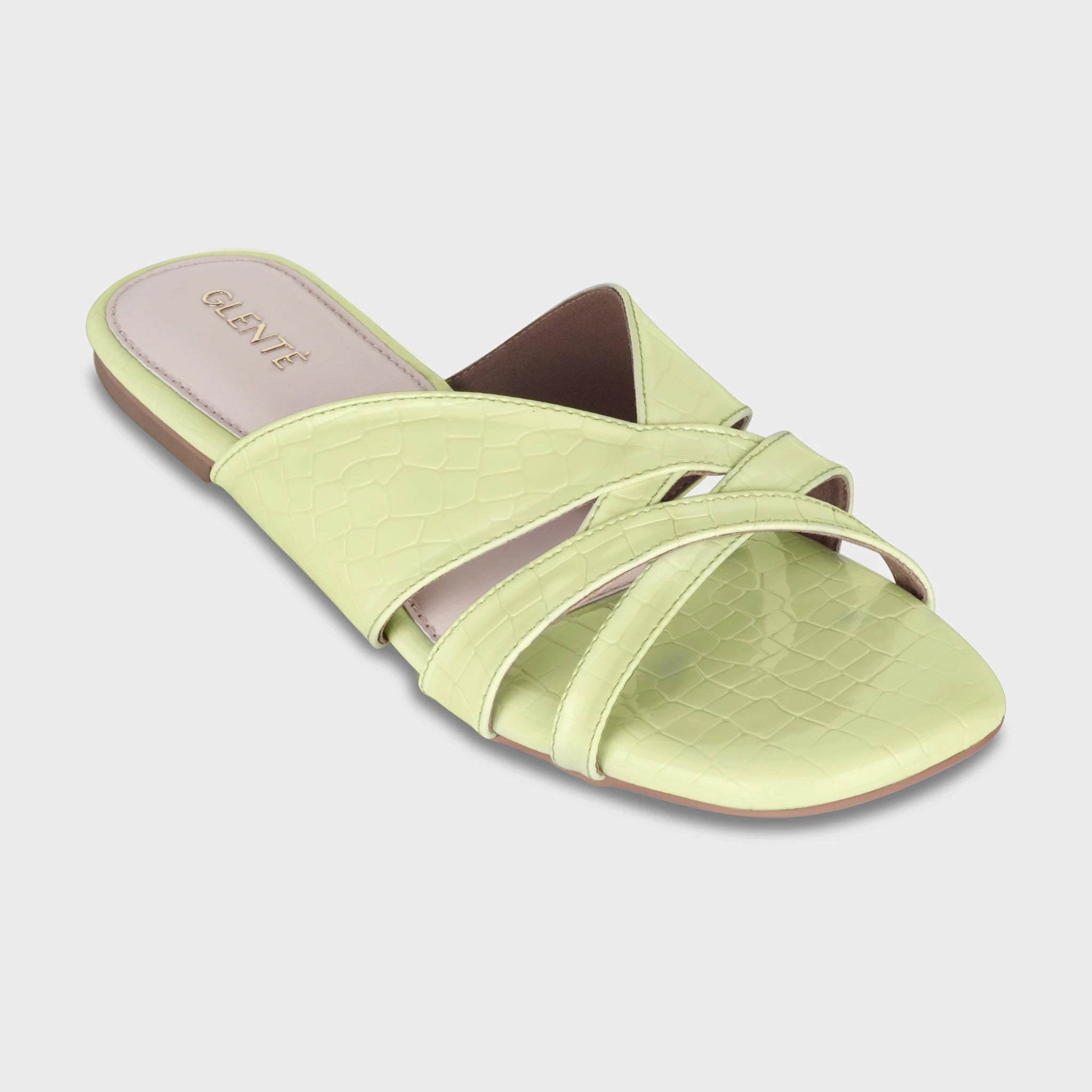 Front angled view of Seraya lime green croc-embossed flat slides highlighting the open toe, interwoven strap construction, and gold Glentè logo on the heel pad