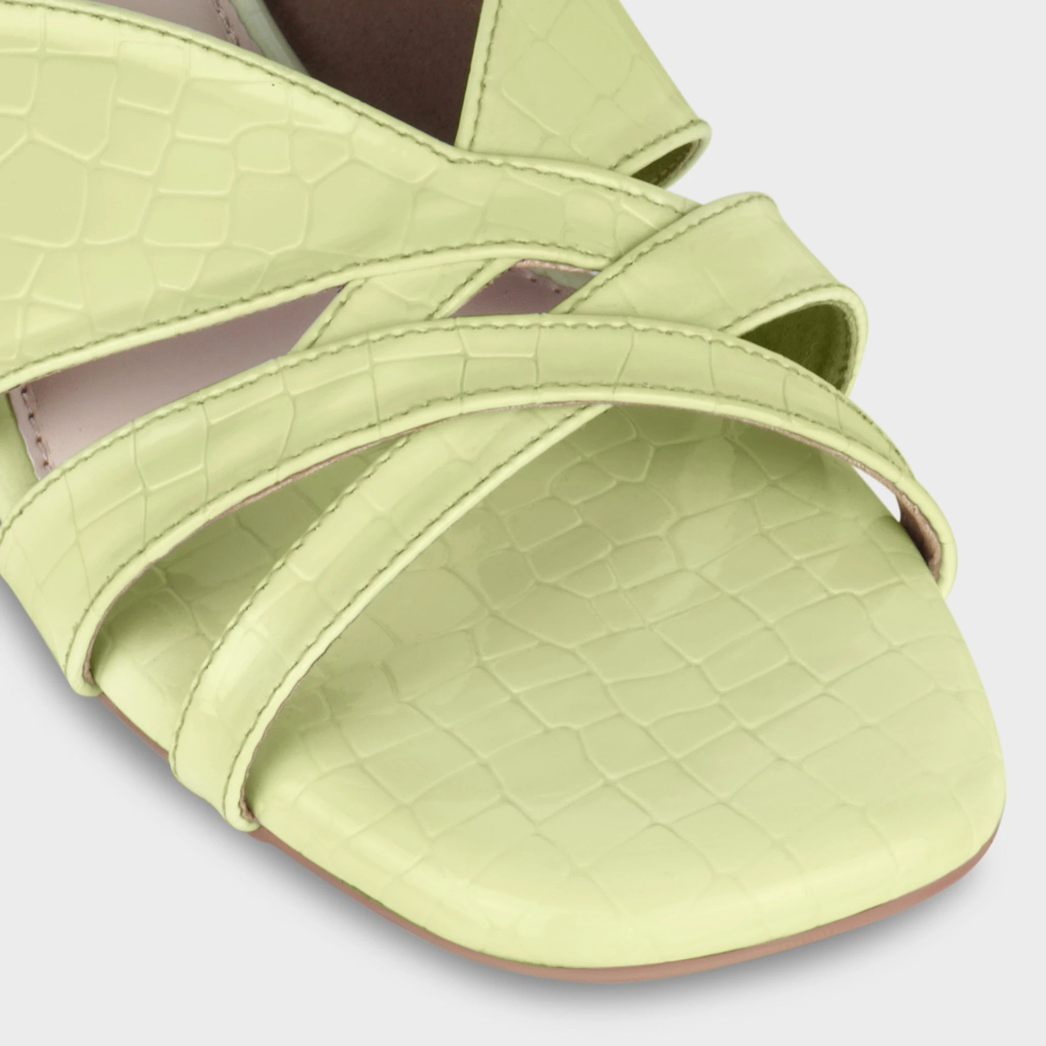 Close-up of the Seraya crossover toe straps showing the croc-emboss pattern detail, layered strap stitching, and matching lime green croc-textured footbed — Glentè