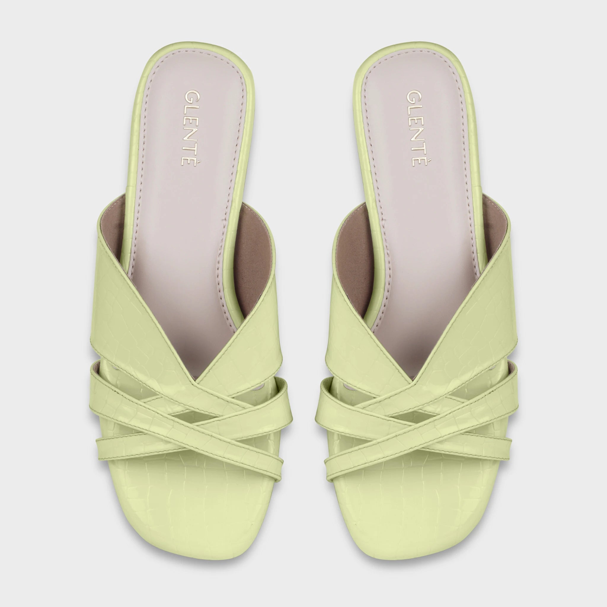 Top-down view of Seraya lime green croc-embossed flat slides as a pair, showing the symmetrical multi-strap crossover design, square open toe, and gold Glentè branding on lavender-toned insoles