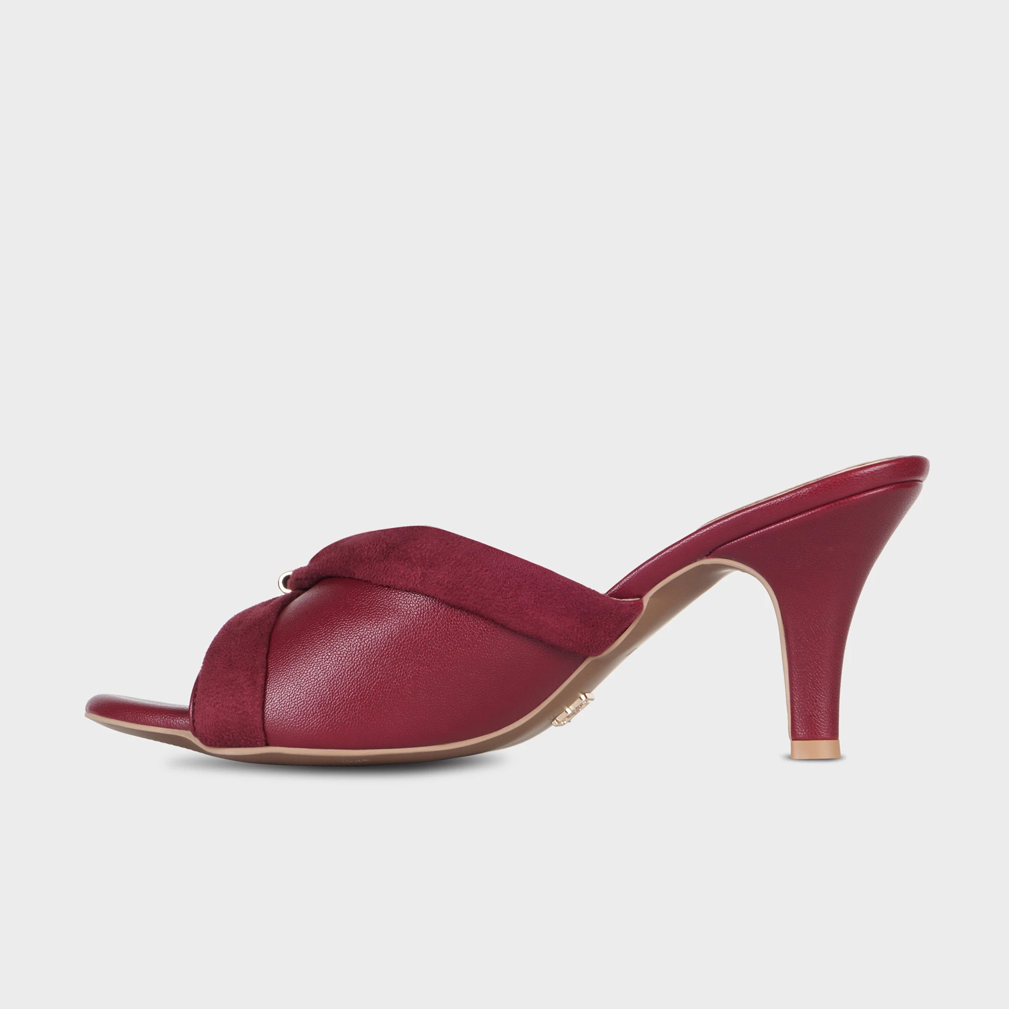 Inner side view of cherry red Solviane heeled mules showing the draped suede bow detail, smooth leather upper, and curved spool heel silhouette — Glentè