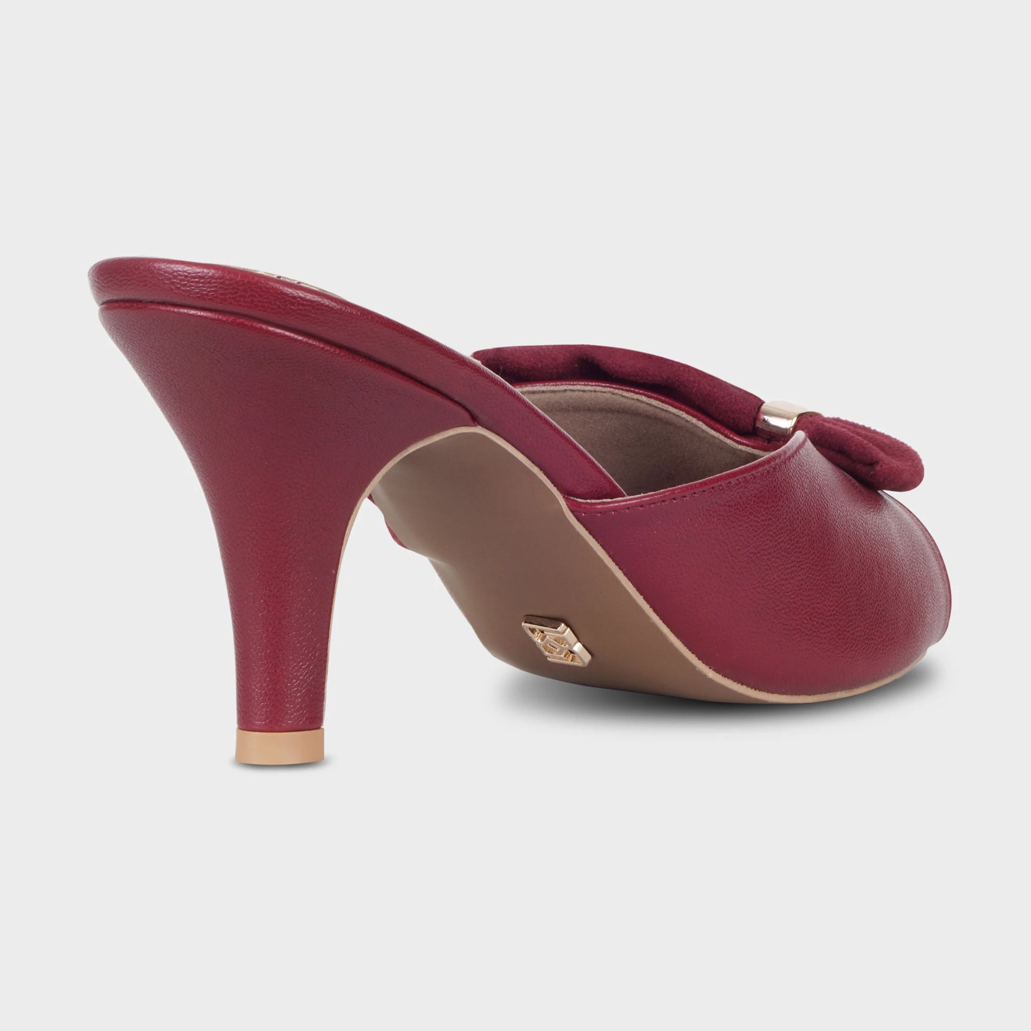 Rear view of Solviane cherry red mules showing the textured leather-wrapped spool heel, gold heel tip, tan outsole with embossed Glentè logo, and suede bow detail at the toe — Glentè