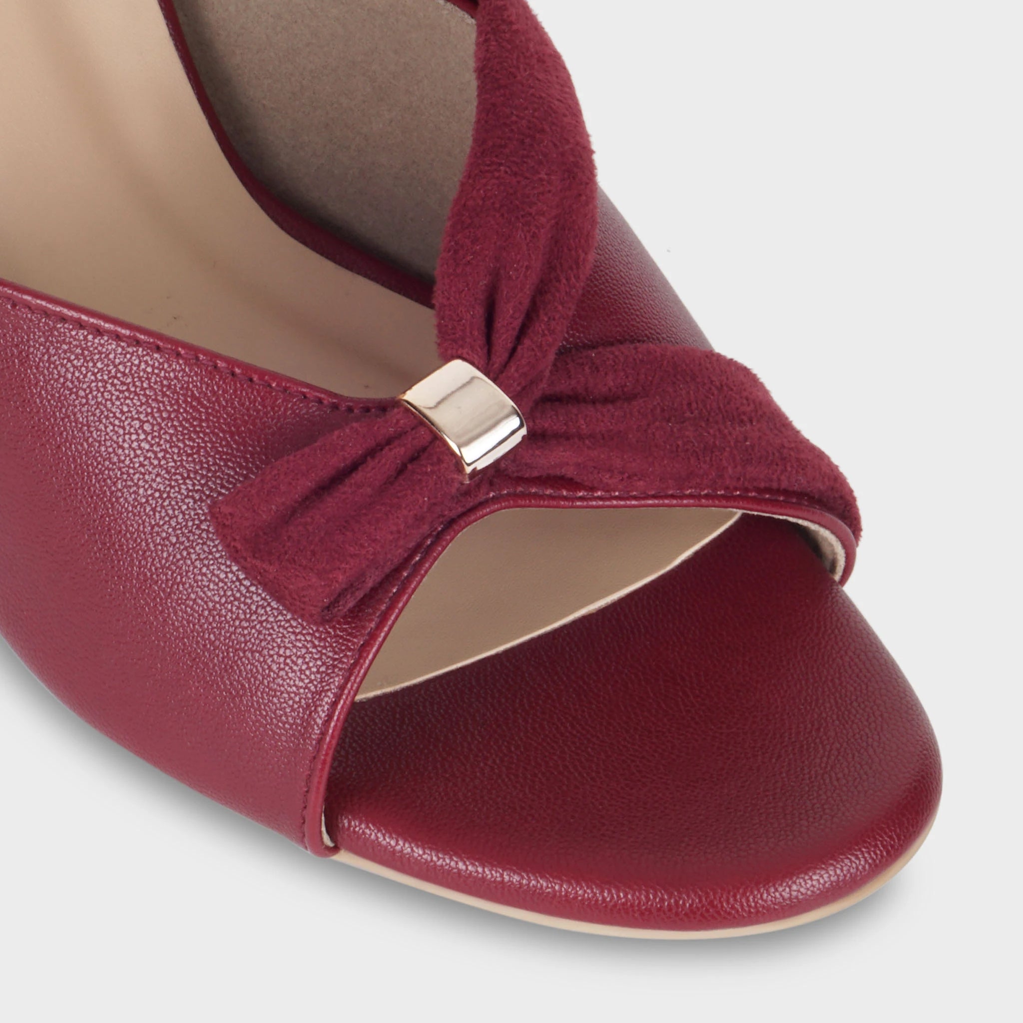 Close-up of the Solviane gathered suede knot detail with polished gold rectangular clasp, showing the contrast between smooth cherry leather upper and soft suede bow — Glentè