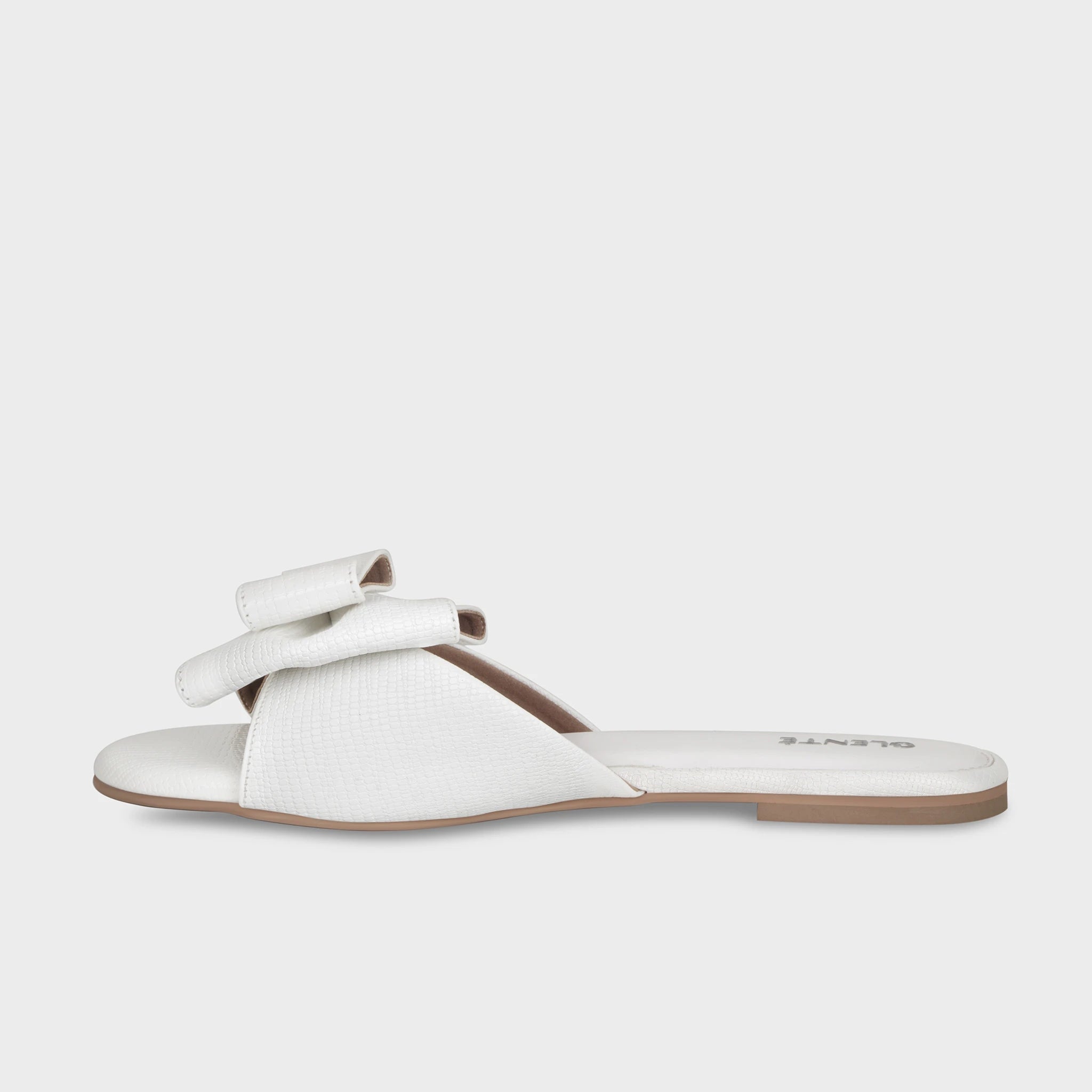 Inner side view of white Alveria flat slides showing the high-gloss lizard-emboss finish, structured bow detail, and clean white outsole - Glentè