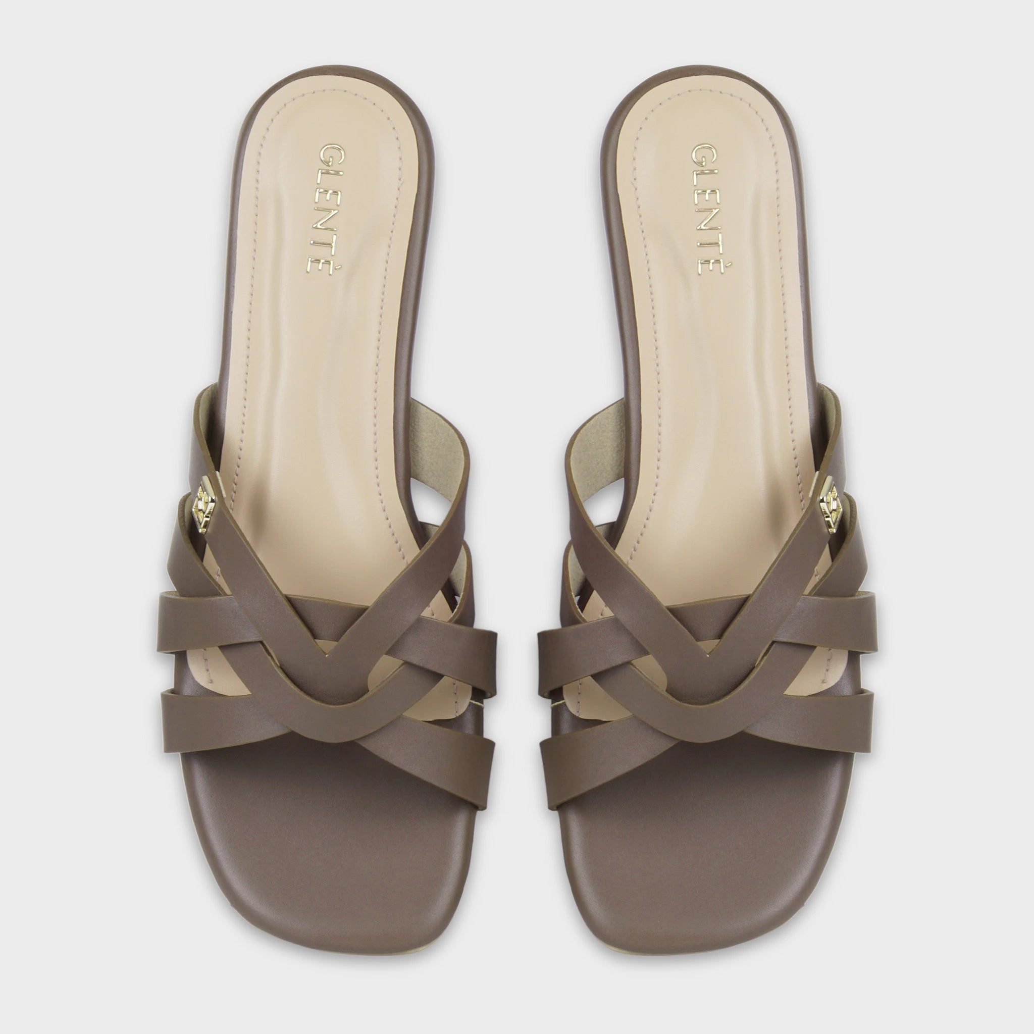Top-down view of Averis brown flat slides as a pair, showing the symmetrical woven multi-strap design, gold Glentè brand buckles, and gold branding on cream insoles