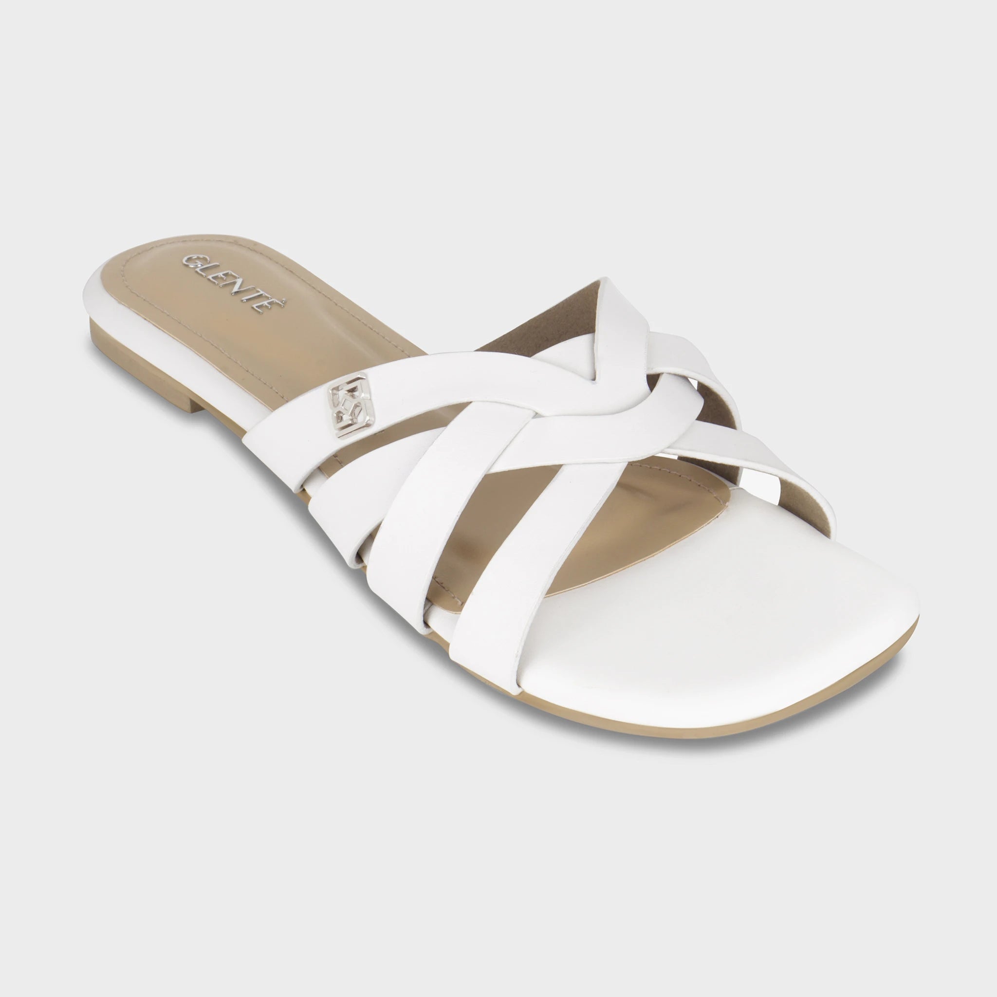 Front angled view of Averis white flat slides highlighting the interlaced woven strap pattern, silver Glentè brand buckle, and silver branding on the beige insole