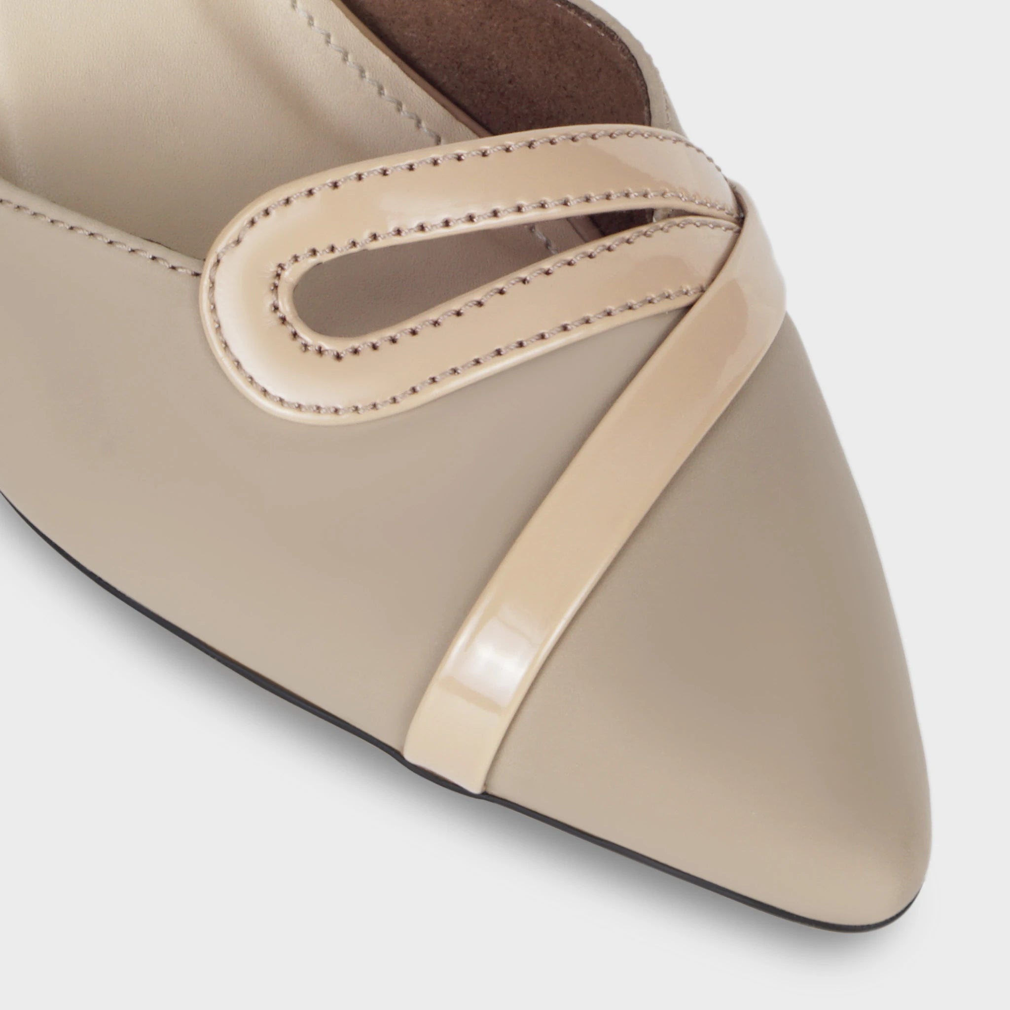 Close-up of the Eloura patent teardrop loop ornament showing the nude glossy open-loop design with detailed edge stitching, sitting over the matte taupe upper — Glentè