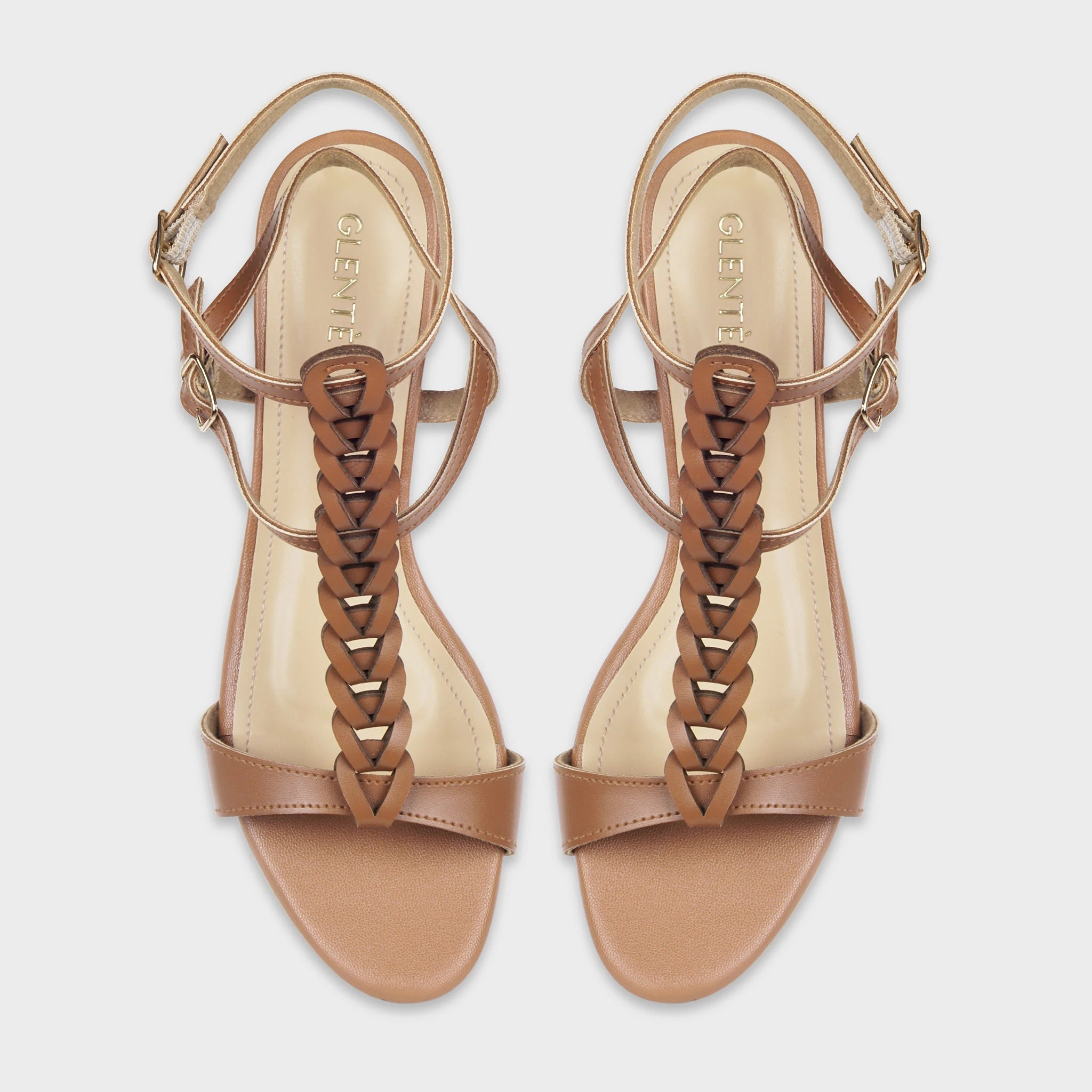 Top-down view of Marvea brown gladiator sandals as a pair, showing the symmetrical braided T-strap design from toe to ankle, open toe bands, dual gold buckle closures, and gold Glentè branding on cream insoles