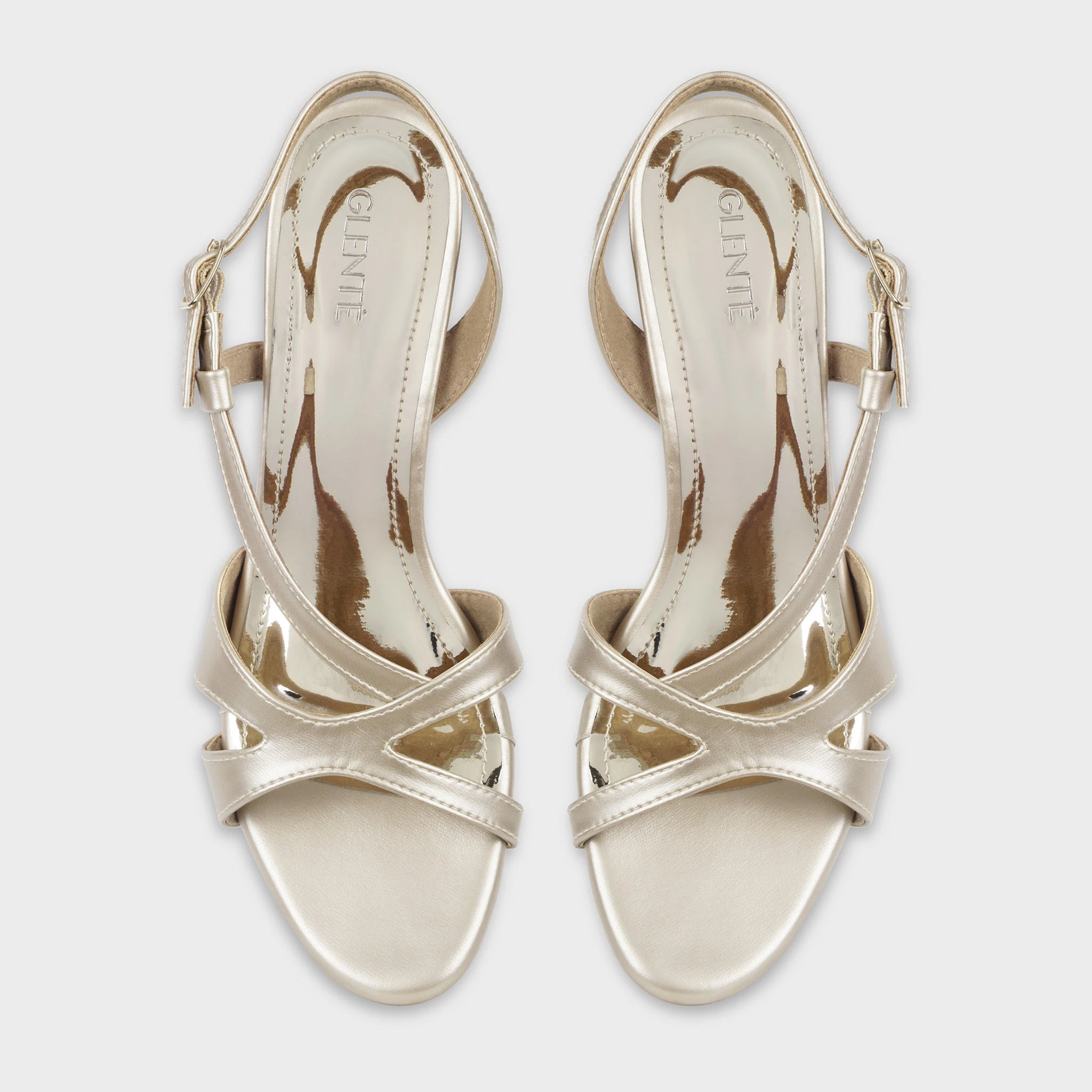 Top-down view of Orisea champagne gold slingback heels as a pair, showing the symmetrical crossover strap pattern, embossed Glentè logo on glossy insoles, and adjustable buckle closures