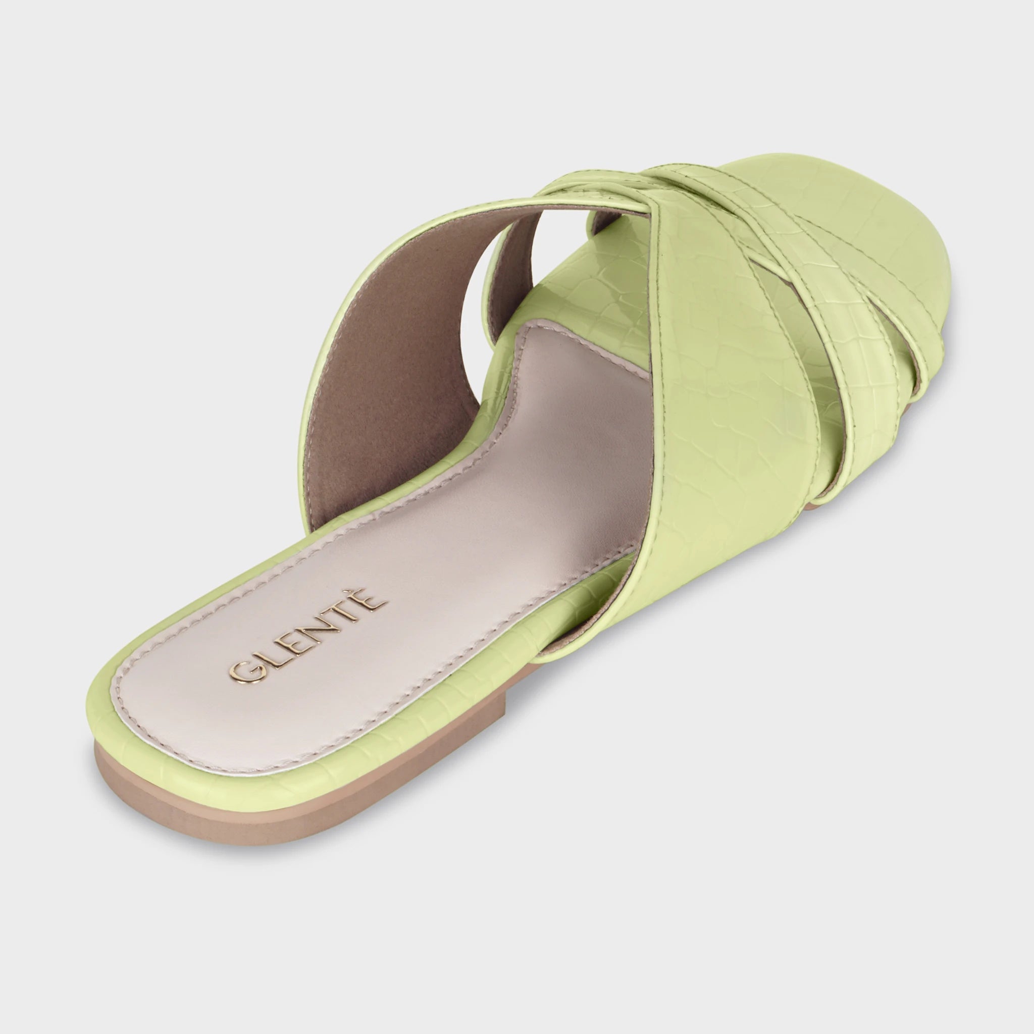 Rear angled view of Seraya lime green flat slides showing the cushioned insole with embossed gold Glentè branding, croc-textured crossover straps, and tan outsole edge