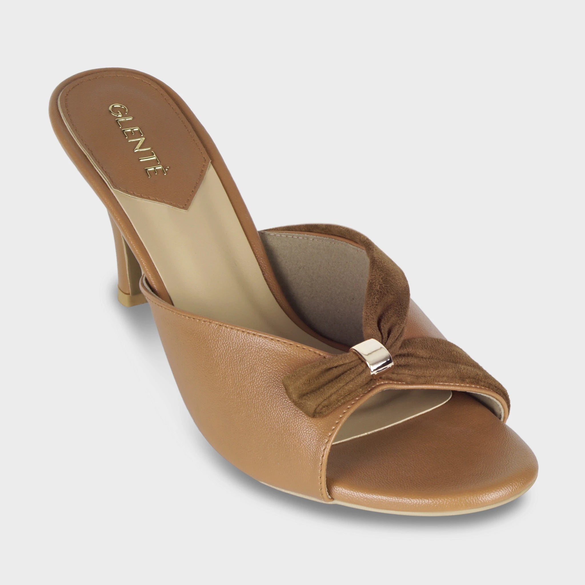 Front angled view of Solviane tan heeled mules highlighting the gathered brown suede knot with gold metal clasp, open toe, and gold Glentè branding on the insole